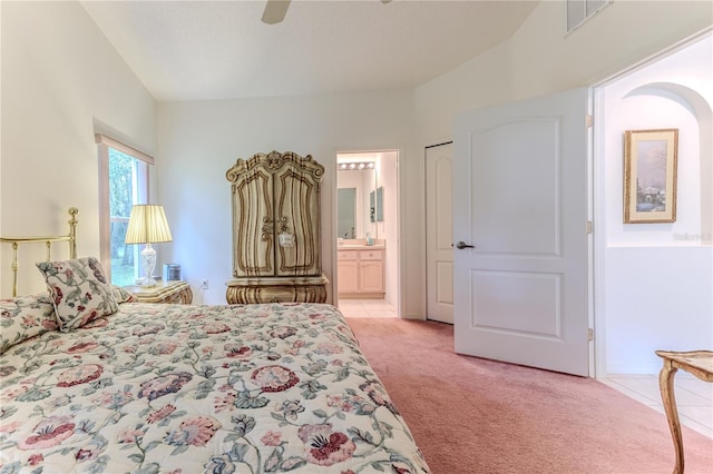 bedroom with light colored carpet, ensuite bath, vaulted ceiling, and ceiling fan