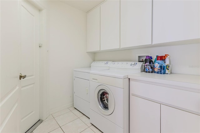 laundry room featuring washing machine and dryer, cabinets, and light tile patterned floors