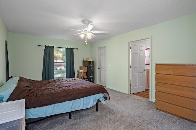 bedroom with ceiling fan, light colored carpet, and a textured ceiling