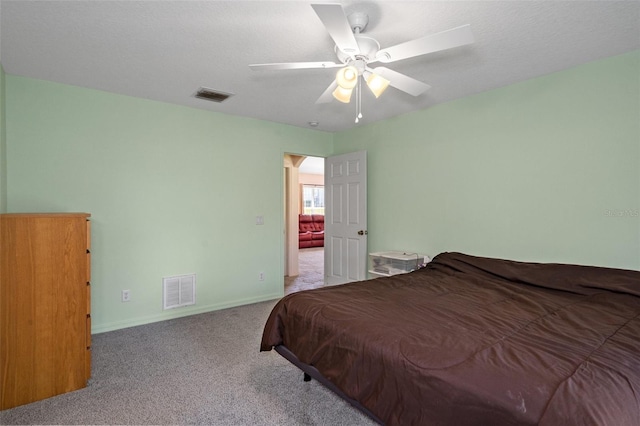 bedroom featuring a textured ceiling, light carpet, and ceiling fan