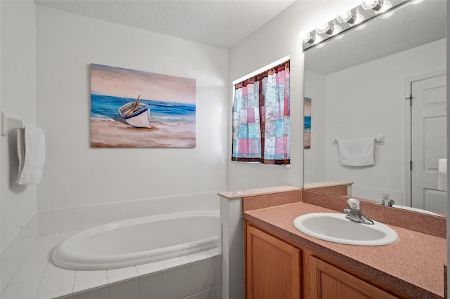 bathroom featuring a textured ceiling, tiled bath, and vanity