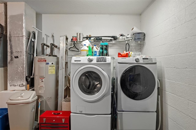 laundry room featuring water heater, a textured ceiling, and washing machine and dryer