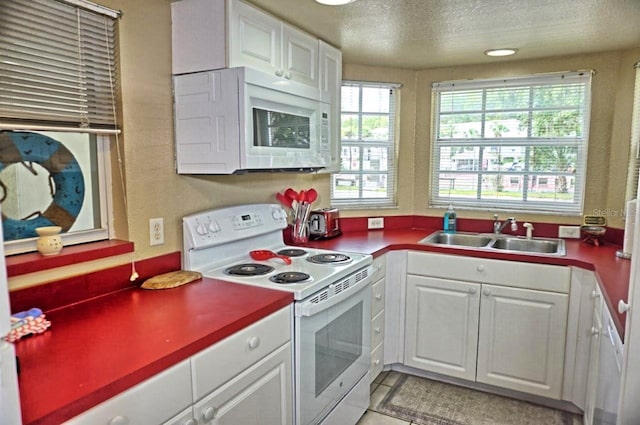 kitchen with a textured ceiling, white appliances, light tile patterned floors, sink, and white cabinetry