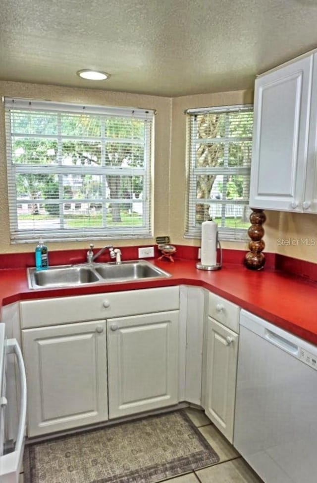 kitchen with white cabinets, white appliances, a textured ceiling, and sink