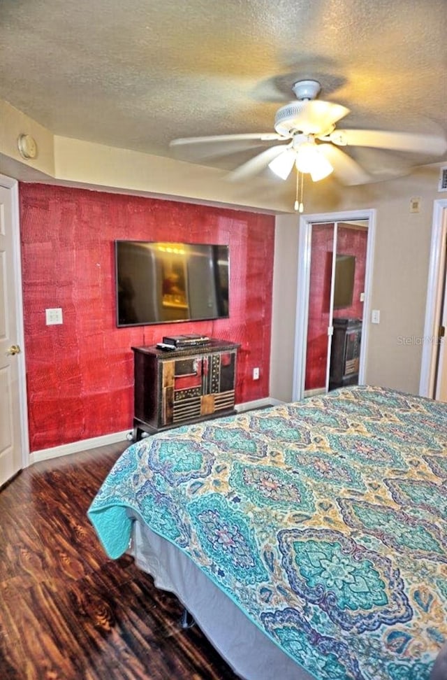 bedroom with hardwood / wood-style floors, ceiling fan, and a textured ceiling