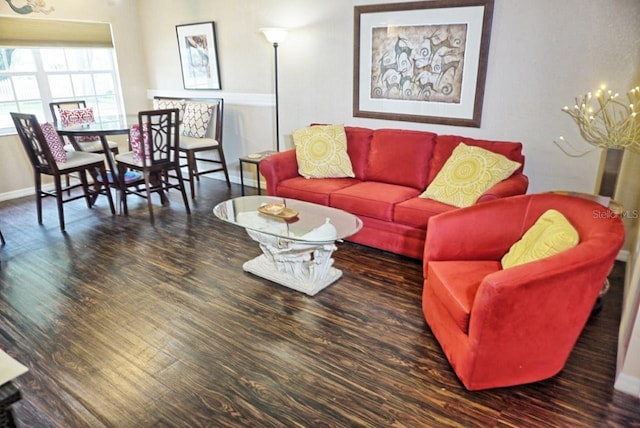 living room featuring a chandelier, baseboards, and wood finished floors