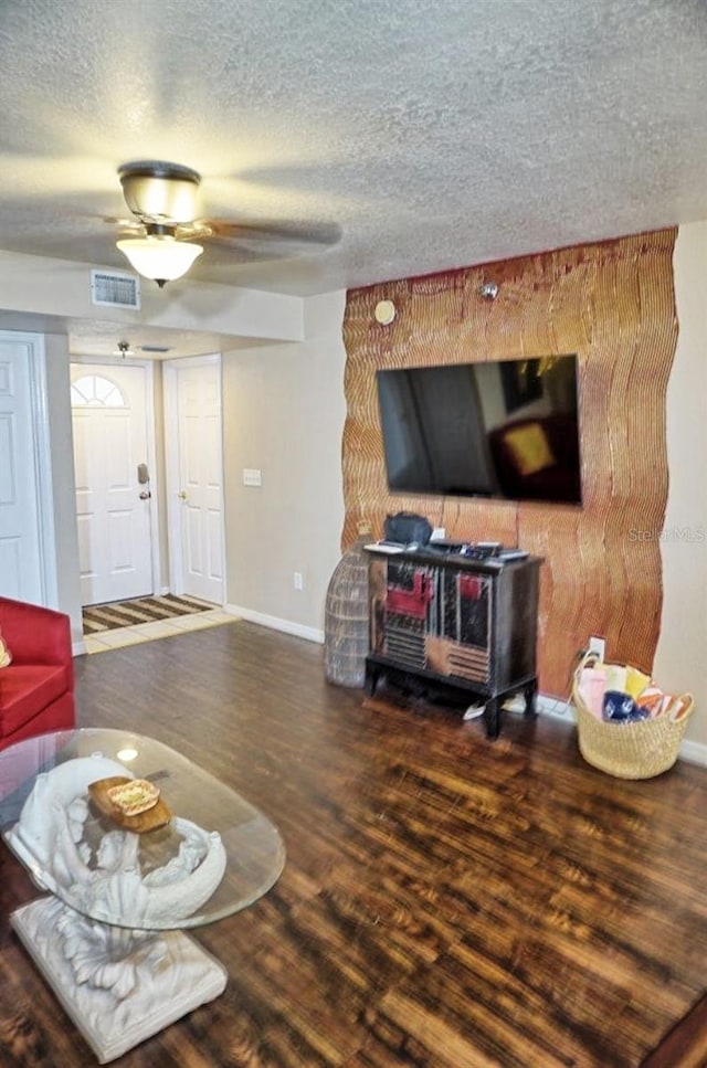 living room with visible vents, a textured ceiling, baseboards, and wood finished floors
