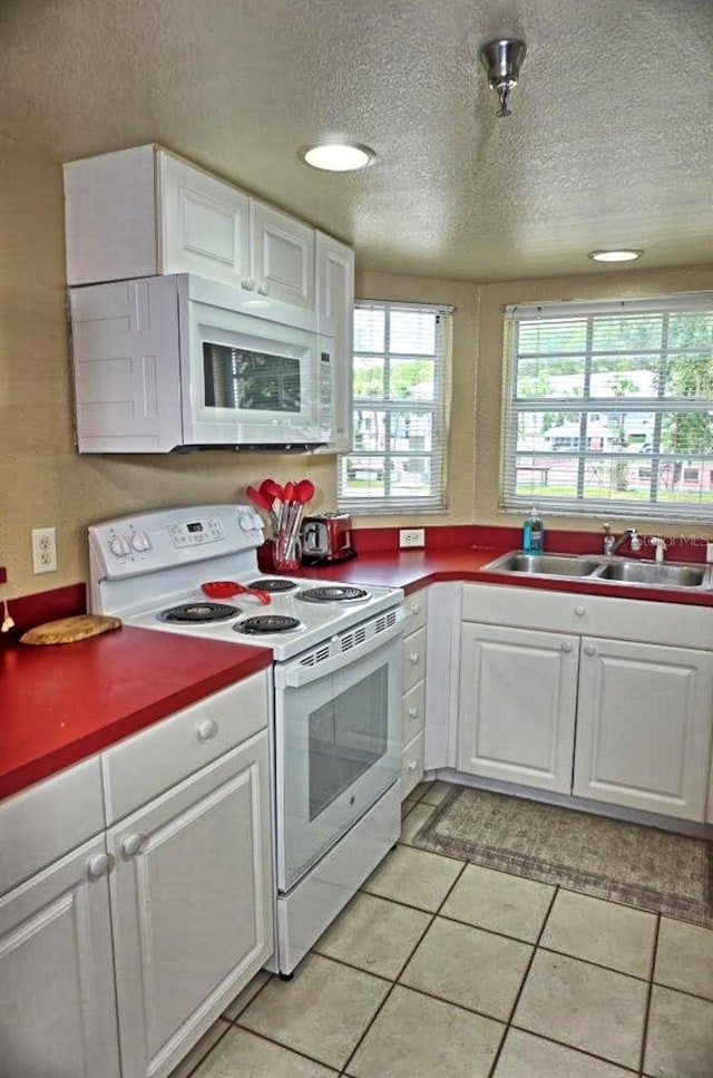 kitchen with a sink, white cabinets, white appliances, and a textured ceiling