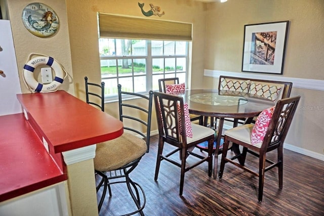 dining room with a textured wall, baseboards, and wood finished floors
