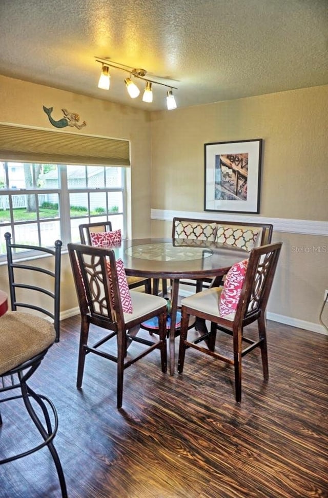 dining area with a textured ceiling, baseboards, and wood finished floors