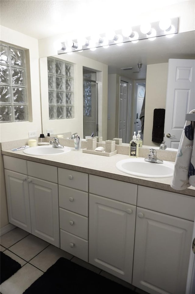 bathroom featuring a sink, a shower stall, tile patterned flooring, and double vanity