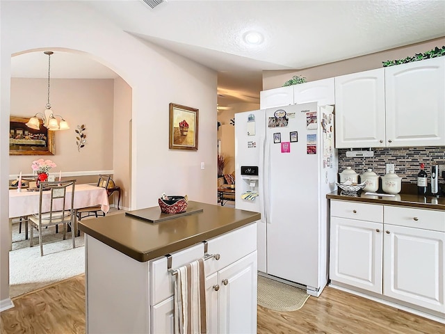 kitchen with white cabinetry, light hardwood / wood-style flooring, a chandelier, and white fridge with ice dispenser