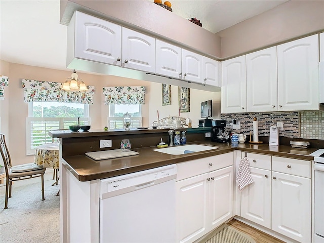 kitchen with white appliances, kitchen peninsula, sink, decorative backsplash, and white cabinets