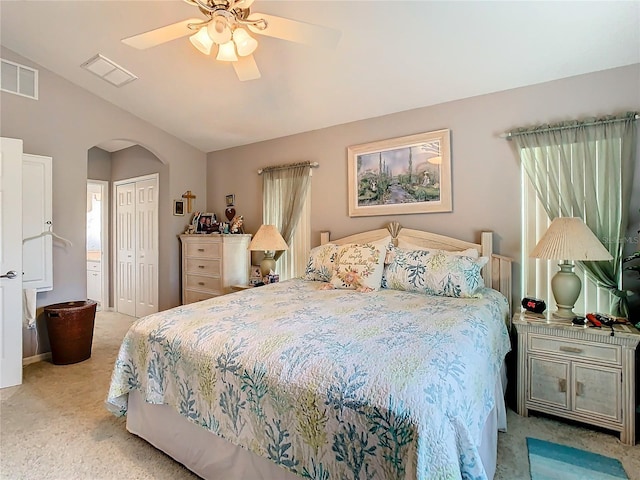 bedroom featuring lofted ceiling, a closet, ceiling fan, and light colored carpet