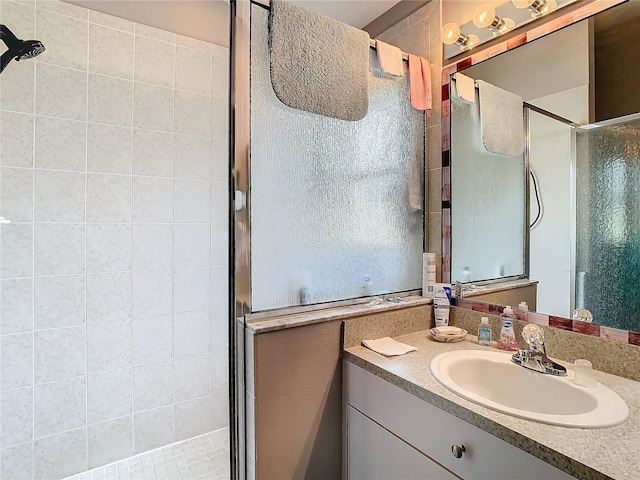 bathroom with a shower with shower door and vanity