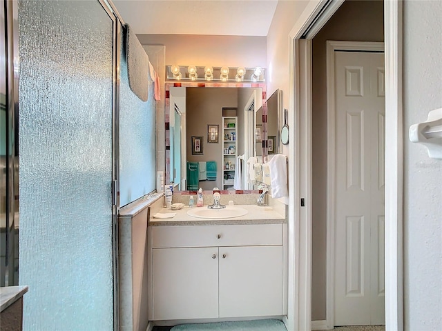 bathroom featuring a shower with door and vanity