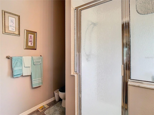 bathroom featuring toilet, an enclosed shower, and hardwood / wood-style flooring