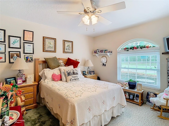 carpeted bedroom with ceiling fan and a textured ceiling