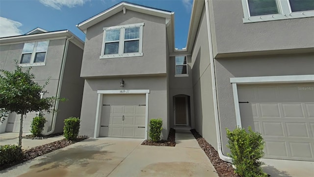 view of front of property featuring a garage, concrete driveway, and stucco siding