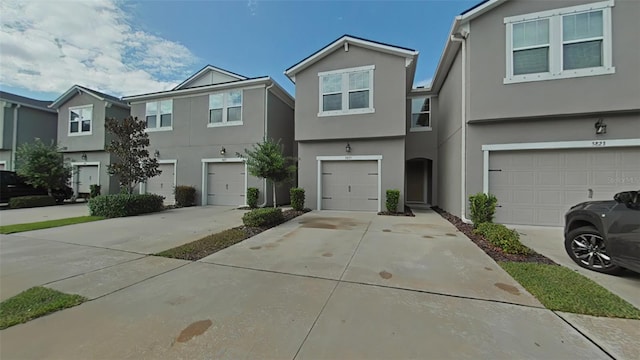 multi unit property featuring a garage, concrete driveway, and stucco siding