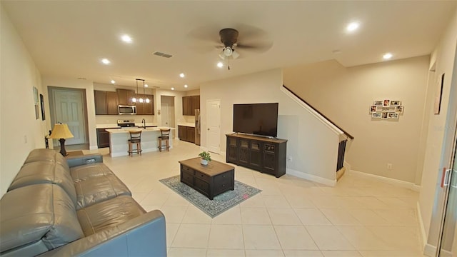 tiled living room featuring ceiling fan and sink