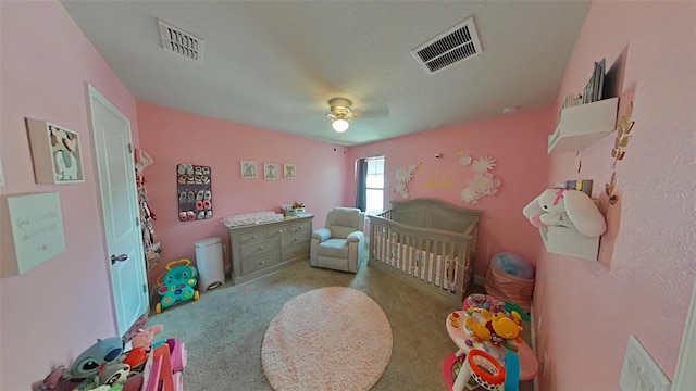 carpeted bedroom with ceiling fan and a crib