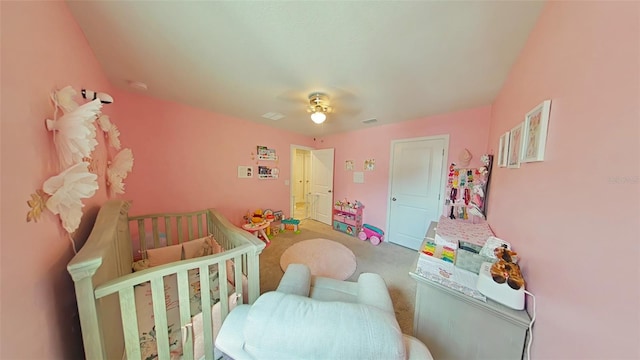 bedroom with a crib, carpet, and ceiling fan