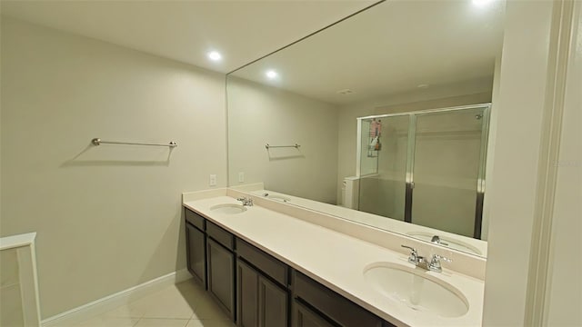 full bathroom with double vanity, a shower stall, baseboards, and a sink