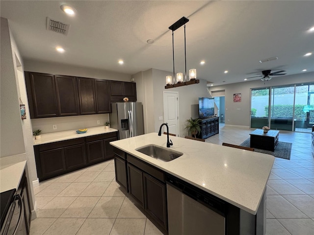 kitchen featuring a kitchen island with sink, stainless steel appliances, a sink, open floor plan, and pendant lighting