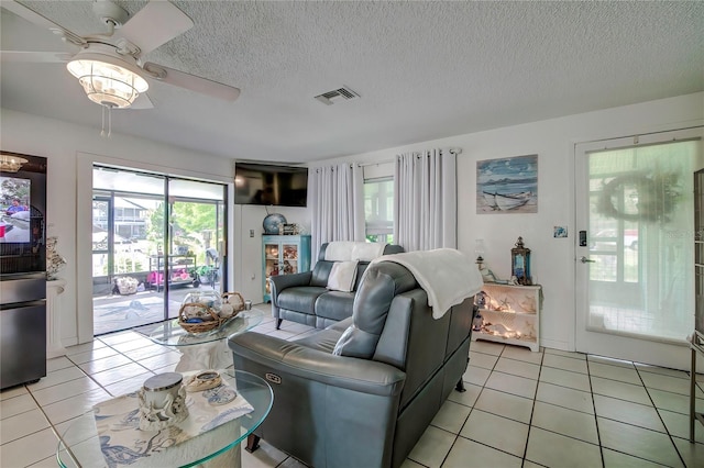 living room with a textured ceiling, light tile patterned flooring, and ceiling fan