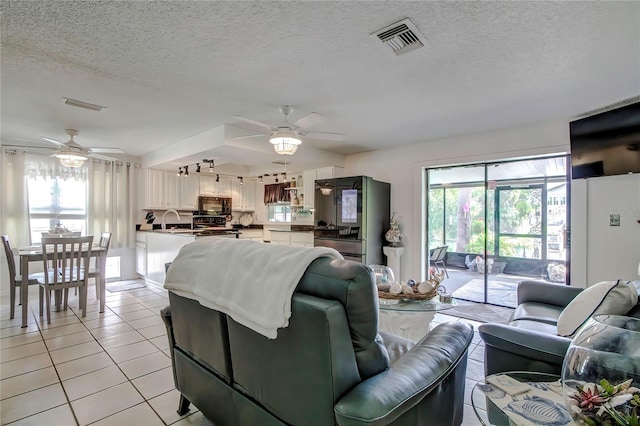 living room featuring a healthy amount of sunlight, sink, light tile patterned floors, and ceiling fan