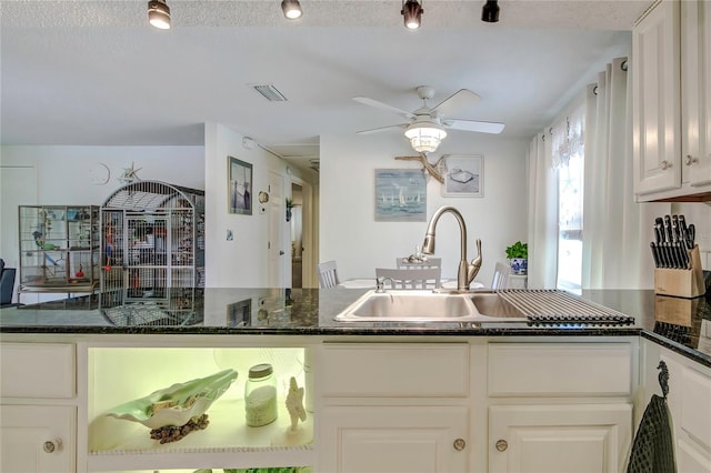 kitchen featuring dark stone counters, a textured ceiling, sink, white cabinets, and ceiling fan