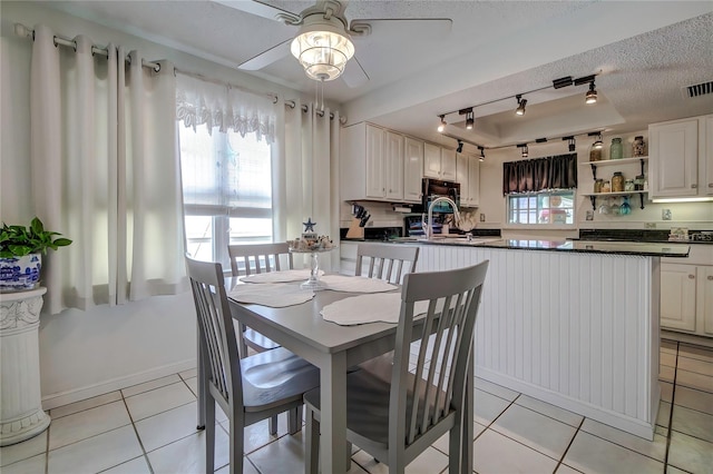 dining room with light tile patterned floors, a textured ceiling, ceiling fan, track lighting, and sink