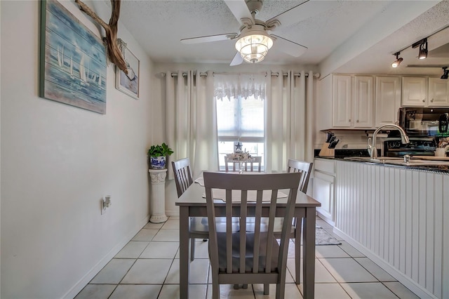 tiled dining area with ceiling fan, track lighting, sink, and a textured ceiling