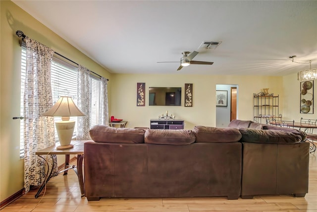 living room featuring ceiling fan with notable chandelier and light hardwood / wood-style flooring