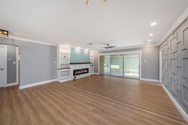 unfurnished living room featuring ornamental molding, light hardwood / wood-style floors, ceiling fan, and a large fireplace