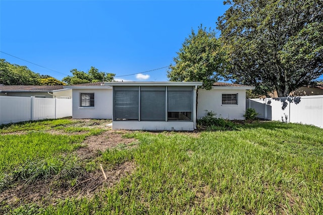 back of property with a yard and a sunroom