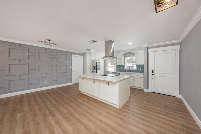 kitchen featuring white cabinets, light hardwood / wood-style floors, stainless steel fridge, a kitchen island, and island range hood