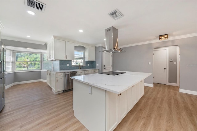 kitchen with white cabinets, a center island, light hardwood / wood-style floors, island exhaust hood, and stainless steel dishwasher