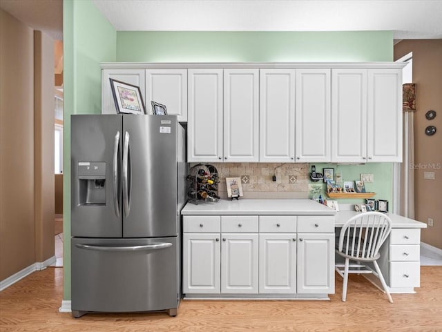 kitchen with light hardwood / wood-style floors, tasteful backsplash, stainless steel fridge with ice dispenser, and white cabinetry