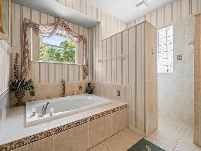 bathroom with a textured ceiling, separate shower and tub, and tile patterned floors