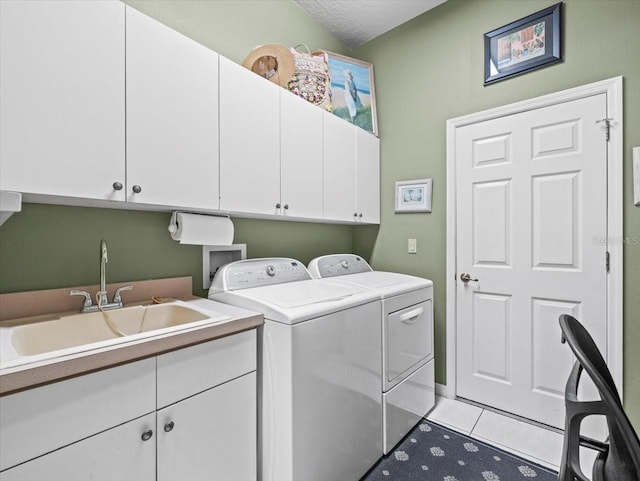 washroom featuring light tile patterned floors, washing machine and dryer, sink, cabinets, and a textured ceiling