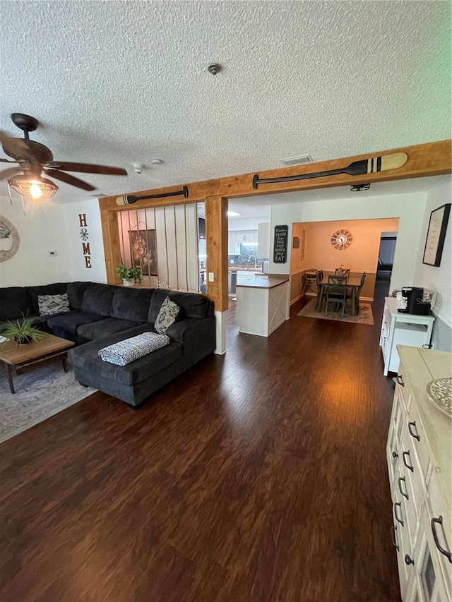 living room featuring a textured ceiling, ceiling fan, and dark hardwood / wood-style flooring