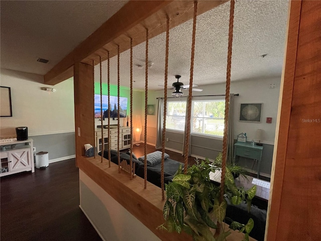 living room with ceiling fan, a textured ceiling, and dark hardwood / wood-style flooring