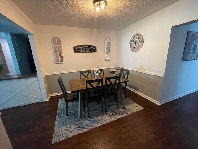 dining area with a textured ceiling and dark hardwood / wood-style floors