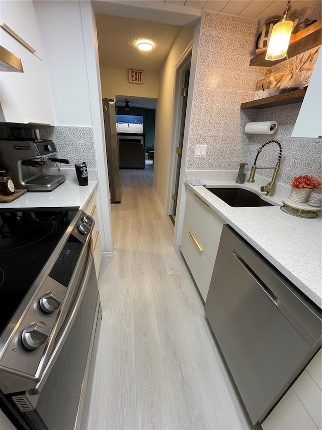 kitchen featuring light hardwood / wood-style floors, tasteful backsplash, sink, hanging light fixtures, and stainless steel appliances