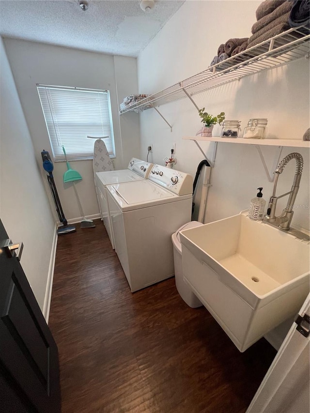 clothes washing area featuring a textured ceiling, dark hardwood / wood-style floors, washer and dryer, and sink