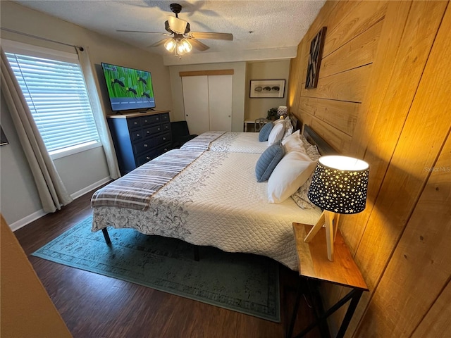 bedroom featuring a textured ceiling, dark wood-type flooring, ceiling fan, and a closet