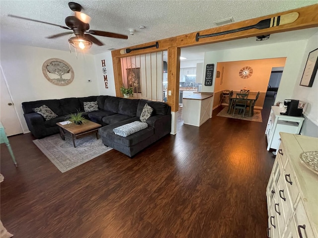 living room featuring a textured ceiling, dark hardwood / wood-style flooring, and ceiling fan