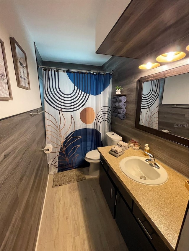 bathroom featuring wood-type flooring, a fireplace, walk in shower, vanity, and toilet